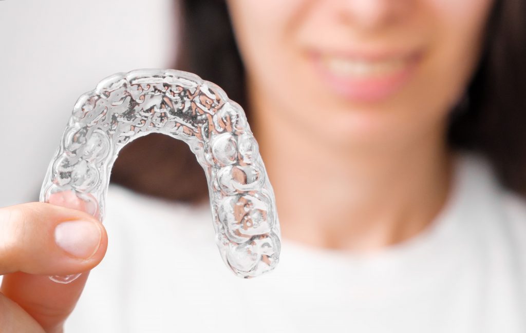 close up orthodontic transparent aligner in womans hand scaled
